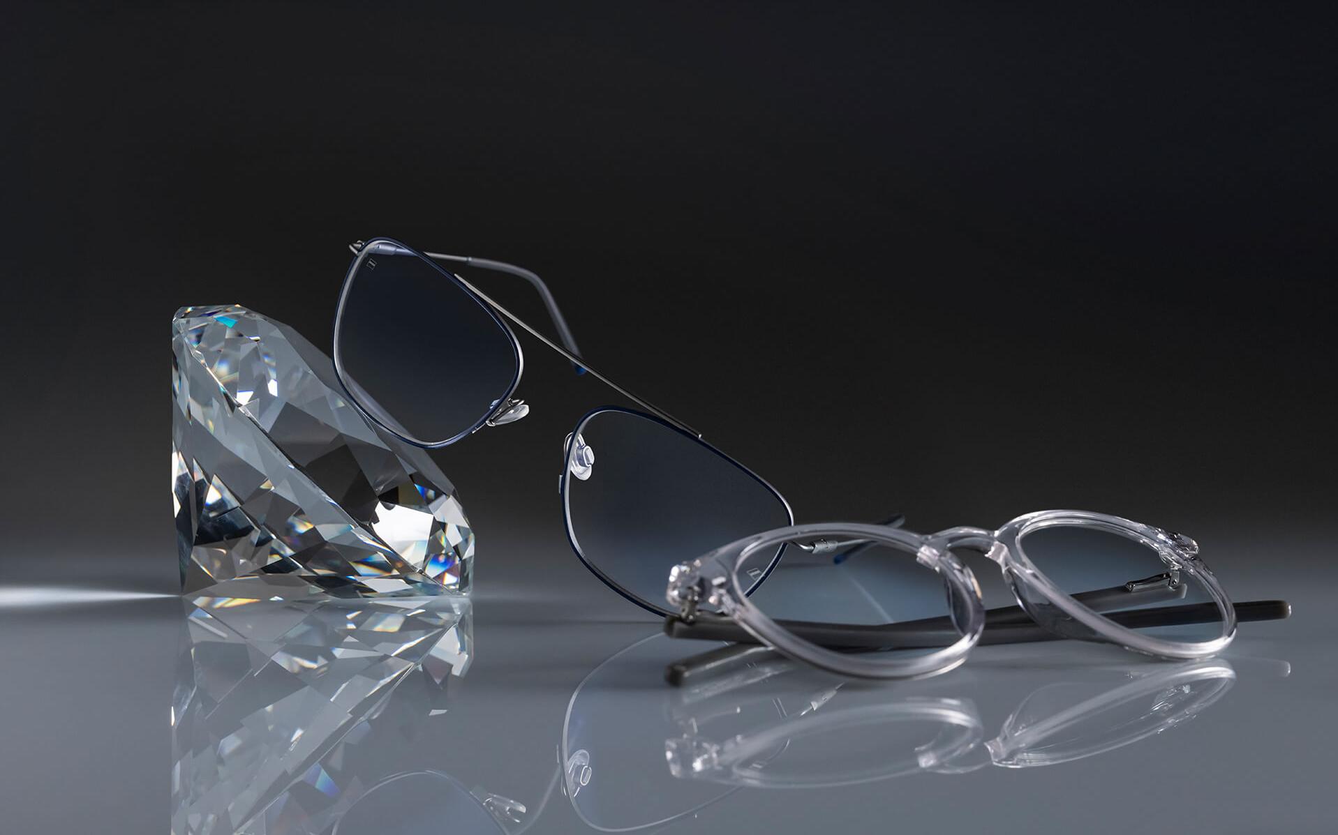 두 벌의 안경에 장착된 자이스 렌즈에 자이스 역사상 가장 단단한 코팅인 듀라비전® 플래티넘이 적용되어 있습니다. 안경 한 벌은 수정에 기대어져 있고 다른 한 벌은 바닥에 놓여 있습니다. 두 벌 모두 투명한 렌즈에 은은한 블루 잔여반사가 나타납니다.