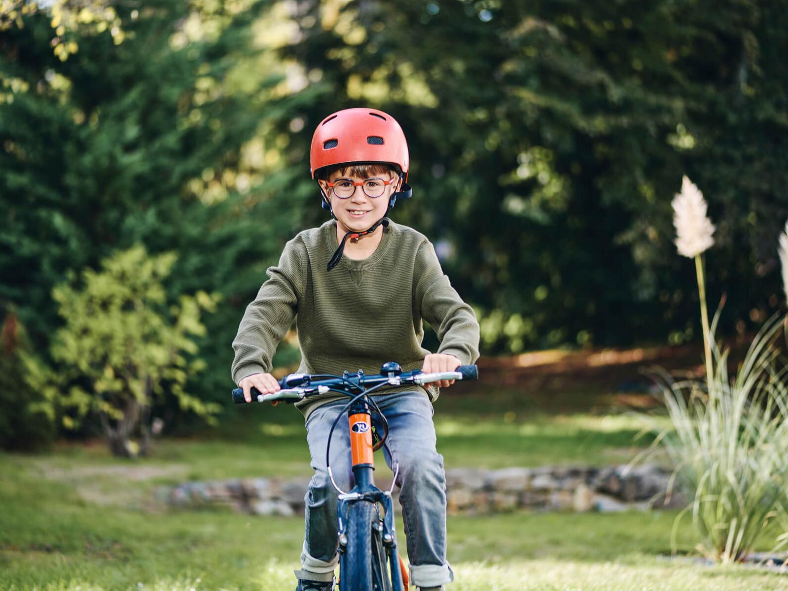 자이스 근시 관리 렌즈를 착용한 어린 소년이 야외에서 자전거를 타고 있다.