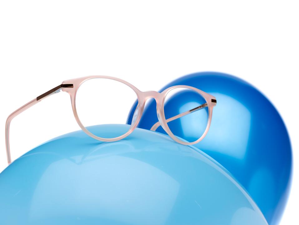 파란색 풍선 위에 자이스 마이오케어 렌즈가 장착된 핑크색 안경 프레임이 놓여 있다.