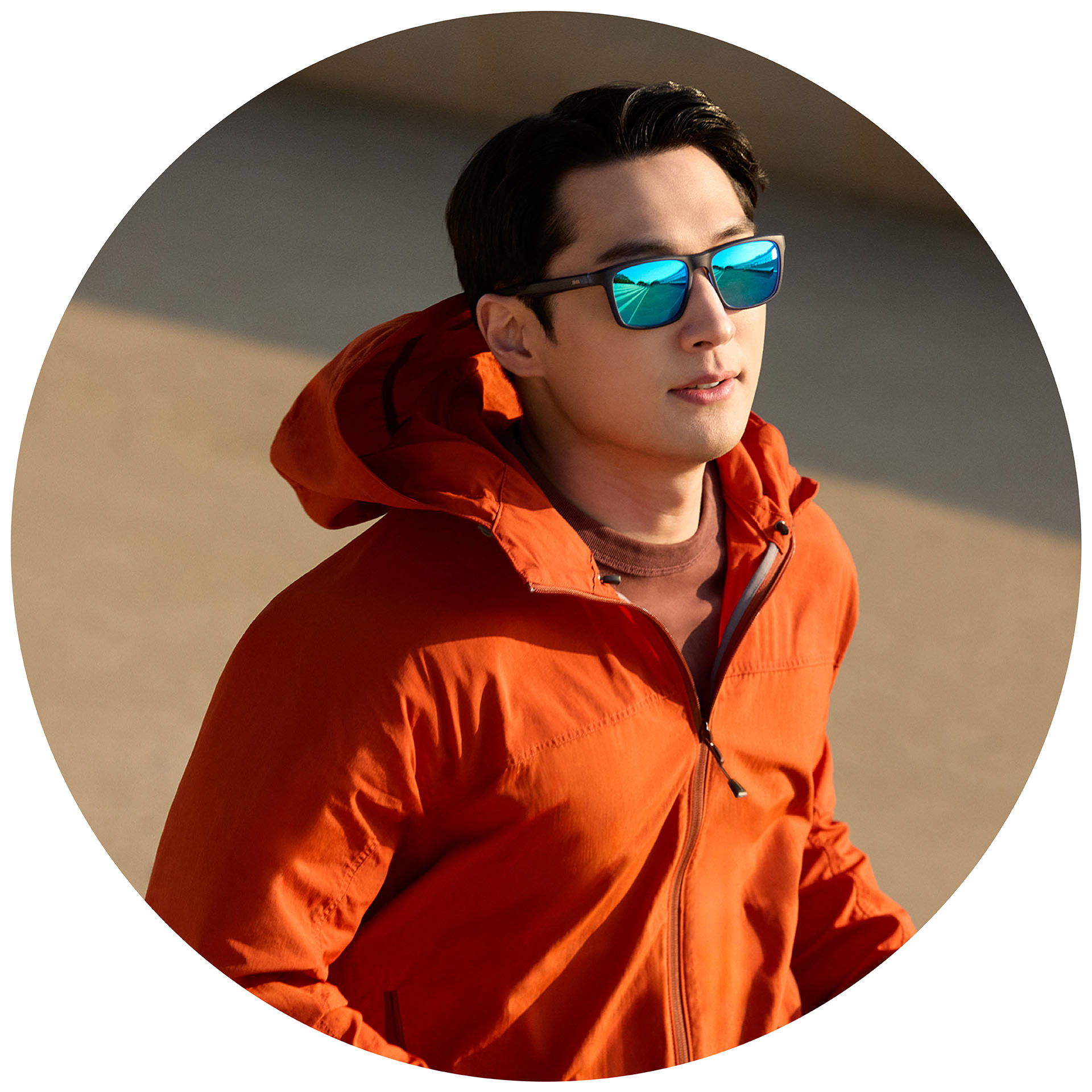 오렌지색 재킷을 입은 남자가 조깅하면서 블루 미러 코팅이 적용된 자이스 도수 선글라스를 착용하고 있다.