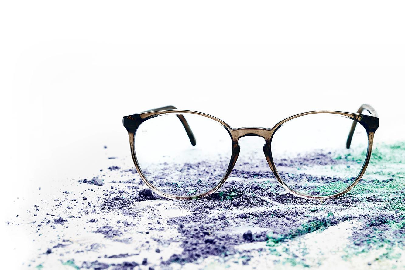 투명 렌즈가 장착된 안경 한 벌이 색가루에 놓여 있다.